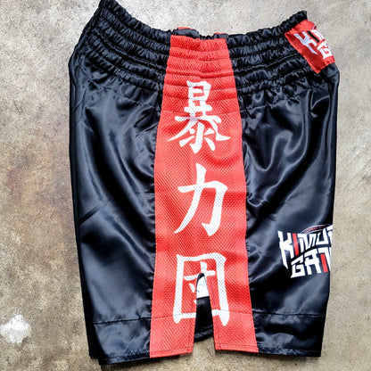 Black shorts with a red belt featuring white characters on a concrete surface