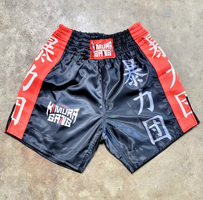 Black shorts with red and white text on a concrete surface