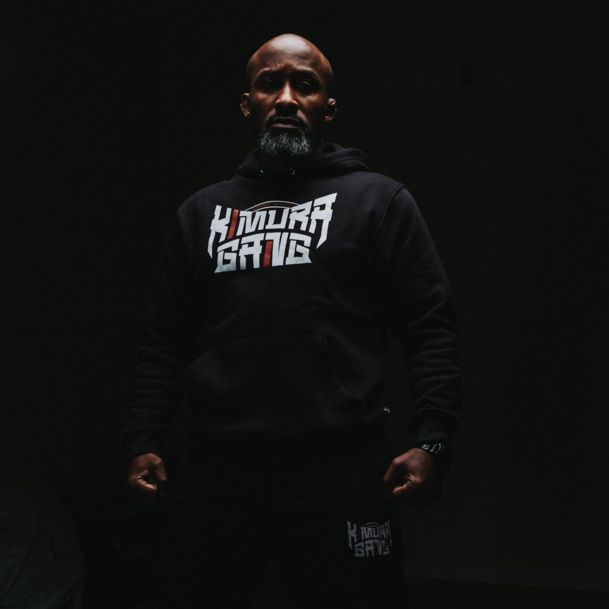 Person wearing a black hoodie with 'Kimora Gang' text on a dark background