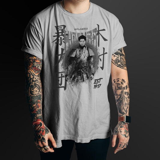 Person wearing a gray t-shirt with a black graphic design and text, standing against a black background.